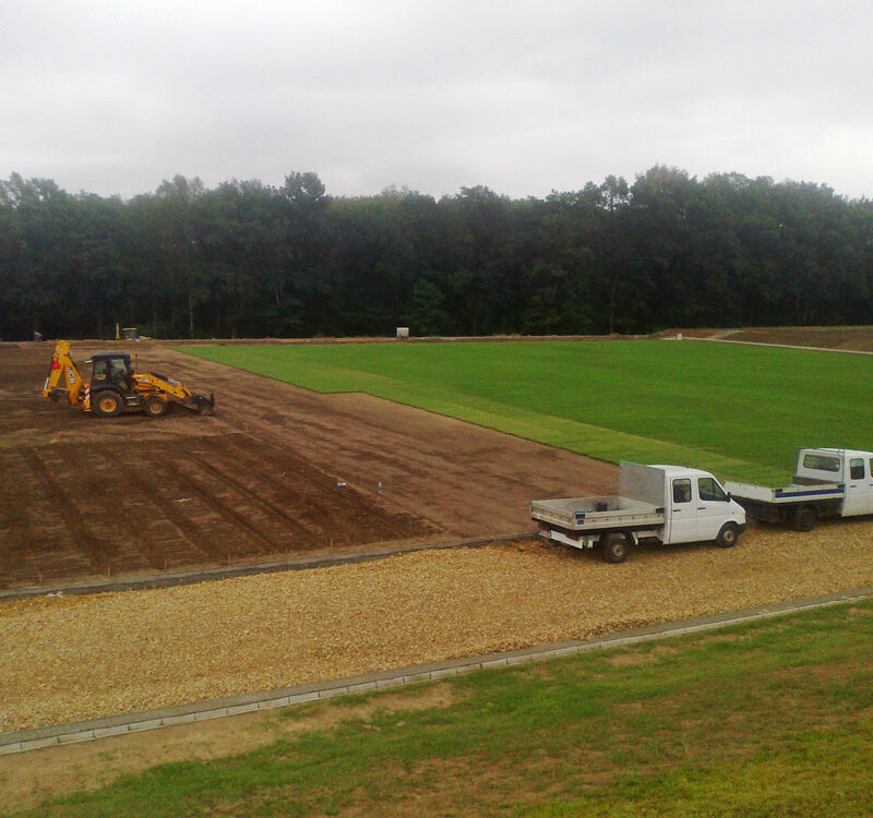 Zdjęcie ukazuje rozwijanie trawy z rolki premium na murawie.