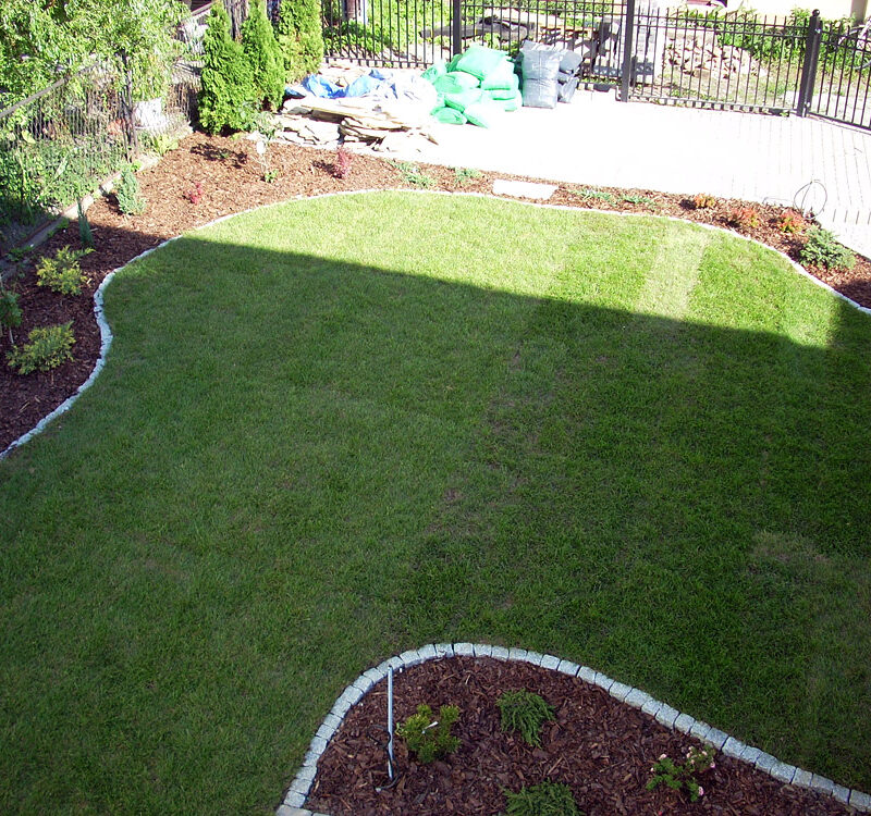 Trawa z rolki premium rozłożona w ogrodzie o bardzo nierównym kształcie.